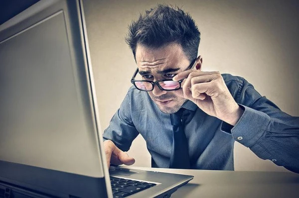 At what distance from the monitor should one sit to reduce eye strain?