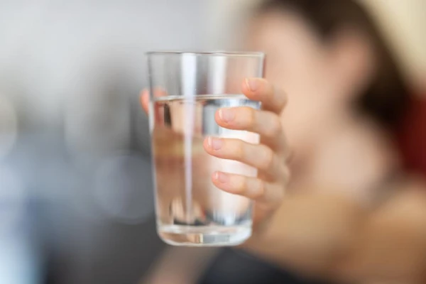How much fluid should be consumed. What type of water contributes to the formation of kidney stones