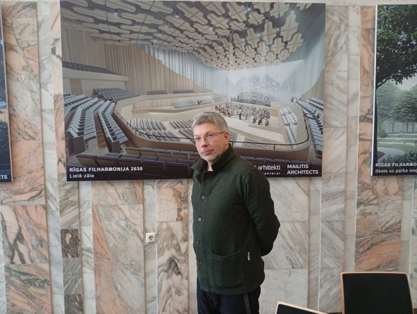 Дирижер Олари Элтс на фоне картинки-визуализации нового концертного зала, который будет построен на месте Дома конгрессов.